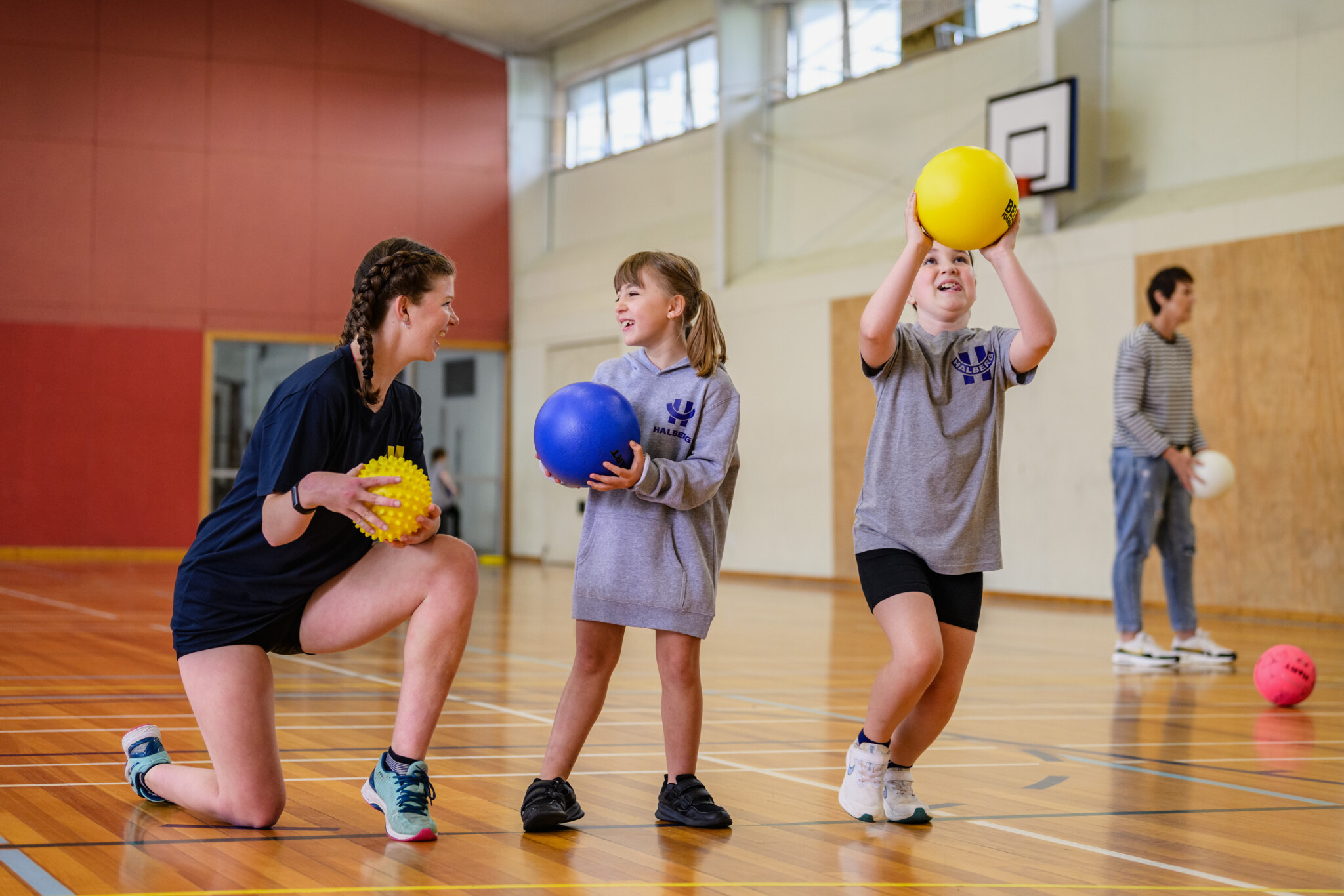 three girls standing in a line shooting basketballs in a school gym.