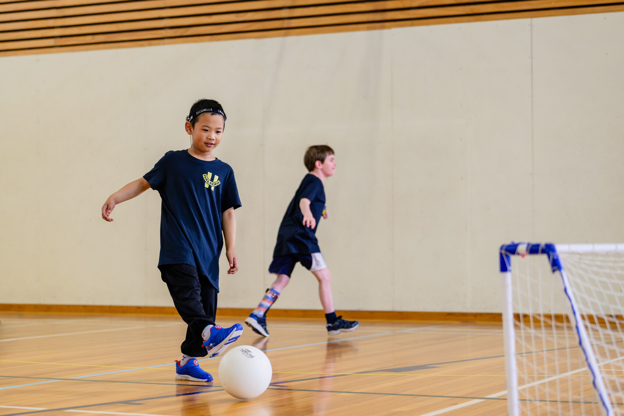Young boy kicks football towards and indoor goal